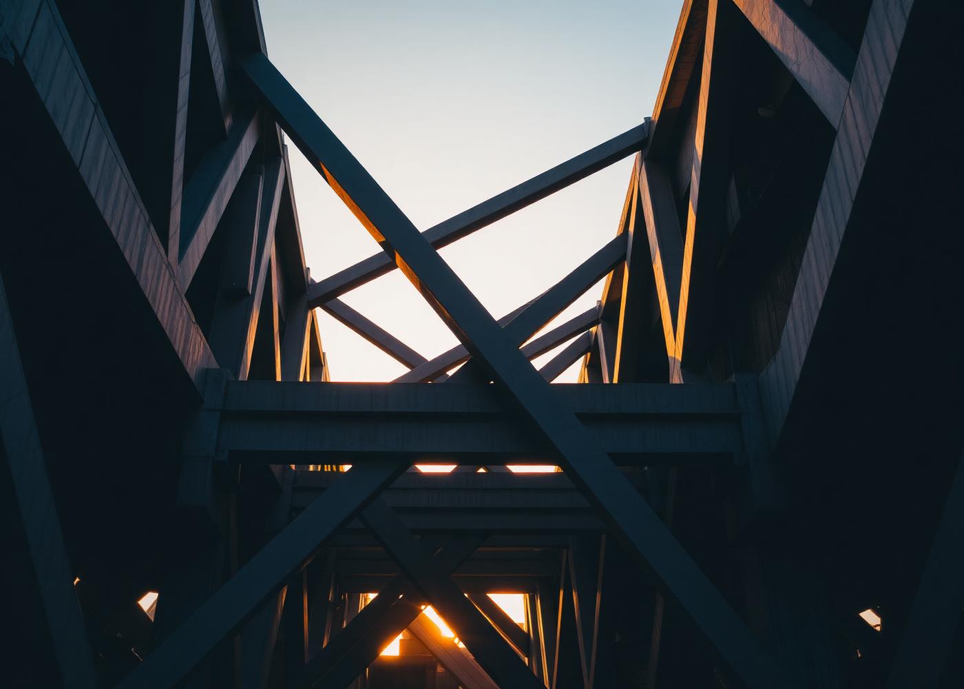 Interlocking steel structural beams silhouetted against a warm evening sky